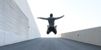 Man jumping on urban road with arms spread wide in Dubai, showcasing freedom and energy.