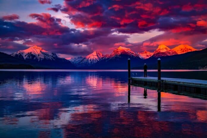 Stunning sunset over a serene lake with colorful sky and majestic mountains.