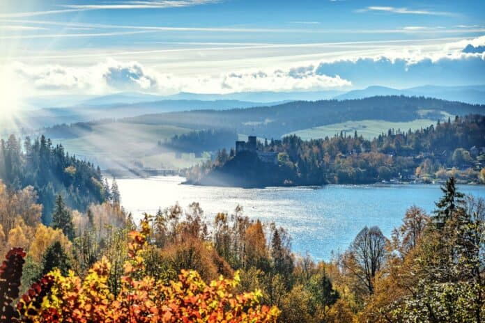 Stunning autumn scenery with sunlit lake and mountains, capturing nature's vibrant colors.